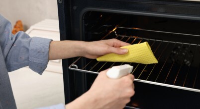 A woman cleans the inside of an oven