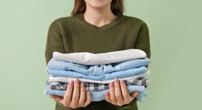 A woman holds a pile of clean folded laundry