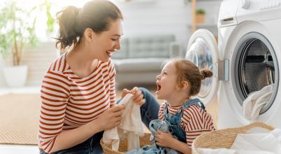 A happy mother and young daughter are doing the laundry