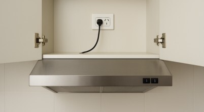 A rangehood beneath a cupboard with the doors open and a power cable plugged into an Australian power point