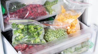A freezer drawer containing frozen fruit and vegetables in zip-lock freezer bags