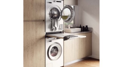 An Asko brand pull-out laundry shelf between an Asko wahsing machine and Asko dryer in a laundry