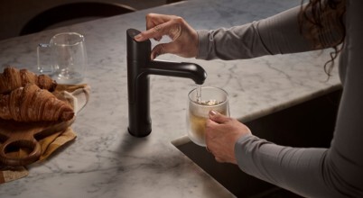 A woman fills a glass teacup with water from a Zip HydroTap