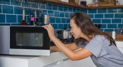 A woman placing food into a microwave