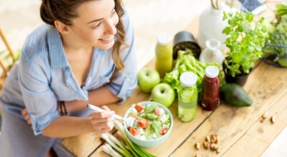 A smiling woman enjoys a fresh salad bowl